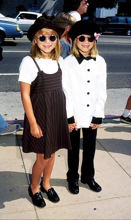 Mary-kate and Ashley Olsen smiling and wearing sunglasses standing together on the sidewalk on 8-11-1996 Mary-kate Olsen and Ashley Olsen 1996 